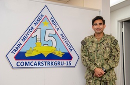 Lt. Anthony Matus stands in front of the entrance of Commander, Carrier Strike Group (CCSG) 15
