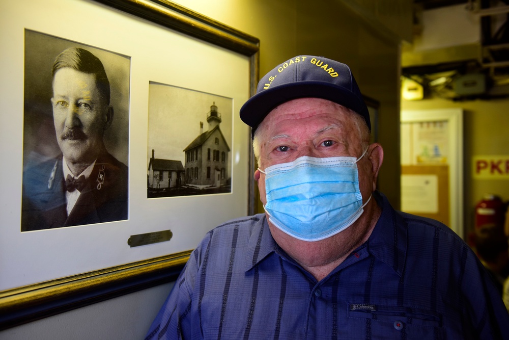 Grandson of historic Coast Guard figure poses next to grandfather's portrait