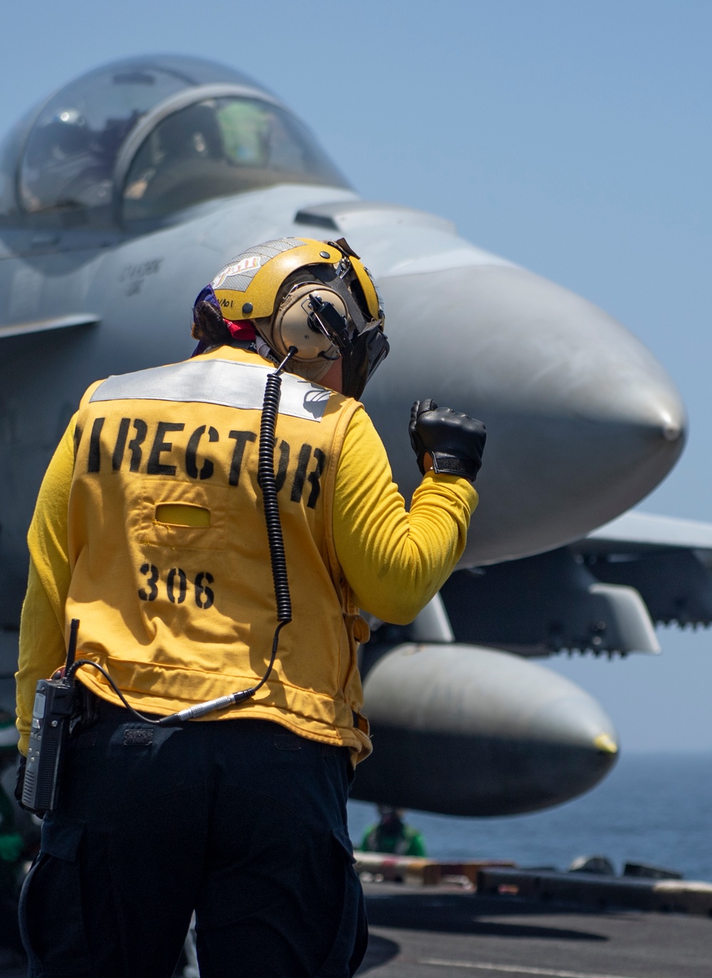 A Sailor signals to an aircraft to remain in place on the flight deck of the aircraft carrier USS Nimitz .
