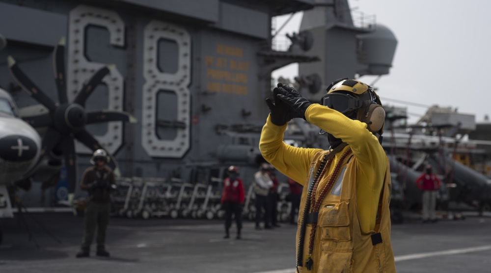 A Sailor signals to an aircraft on the flight deck of the aircraft carrier USS Nimitz (CVN 68).