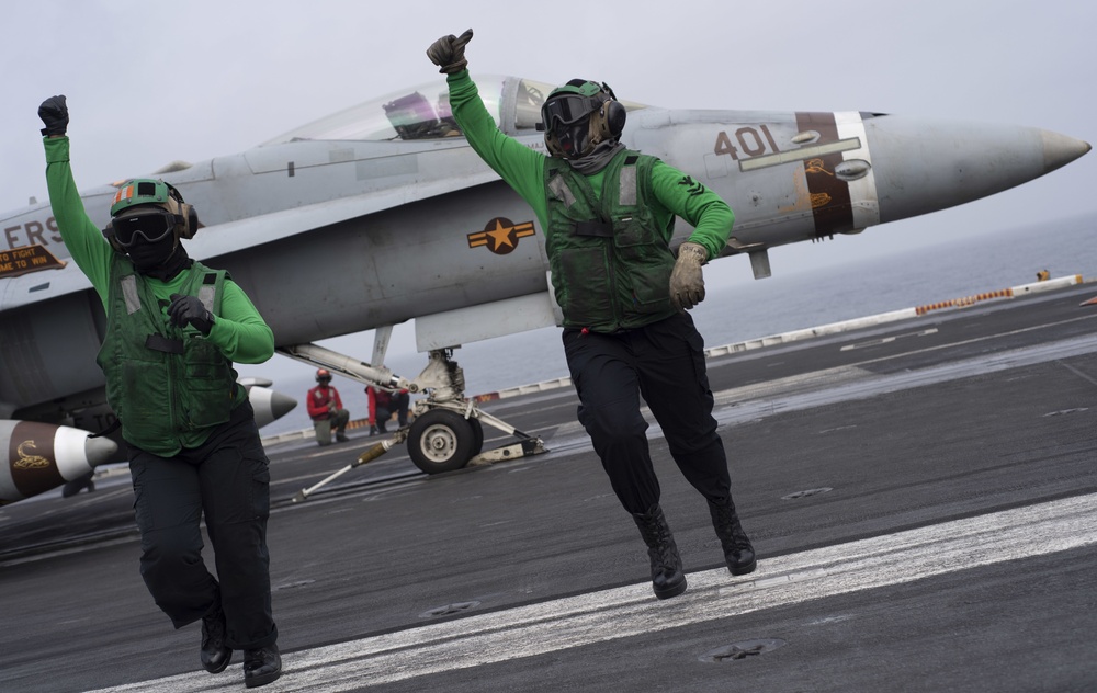 Sailors signal an aircraft is cleared to launch.