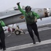 Sailors signal an aircraft is cleared to launch.