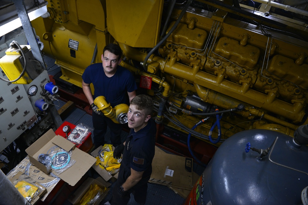 Coast Guard crew members perform pre-patrol repairs and maintenance