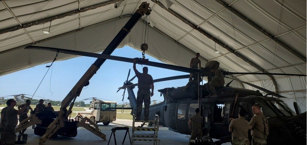 Soldiers conduct maintenance on a UH-60 Black Hawk helicopter using a self-propelled crane aircraft maintenance and positioning II expeditionary crane.