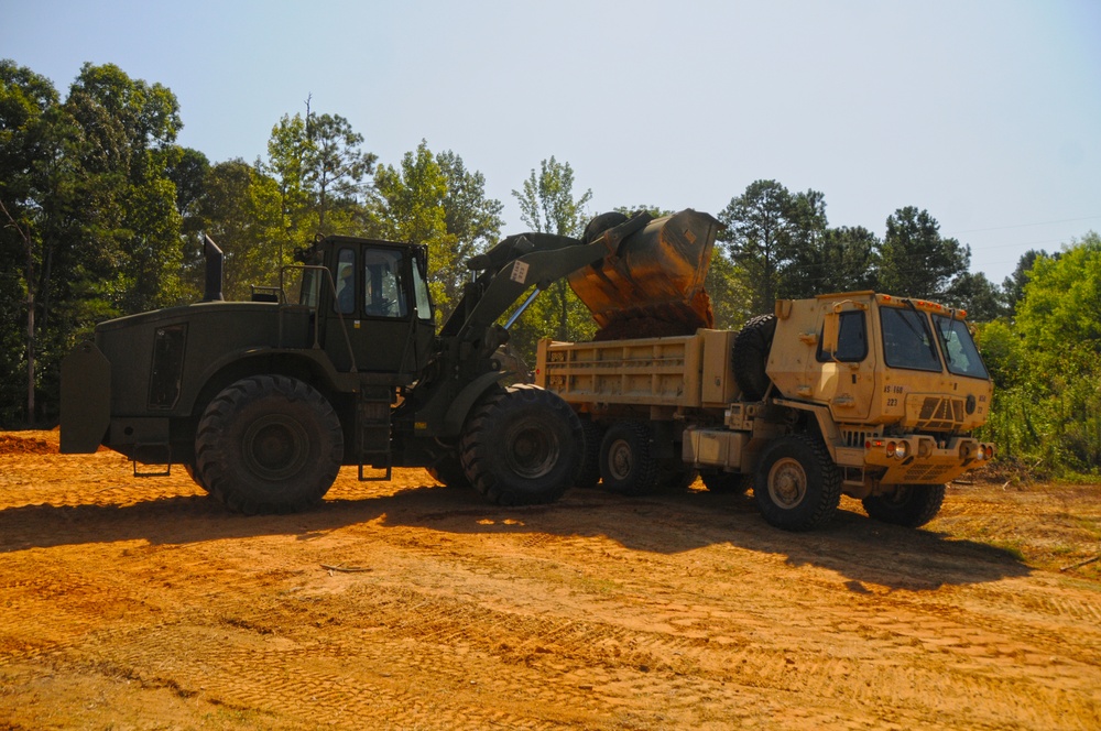 966H Scoop Loader filling an M1157A1P2 Dump Truck with soil 