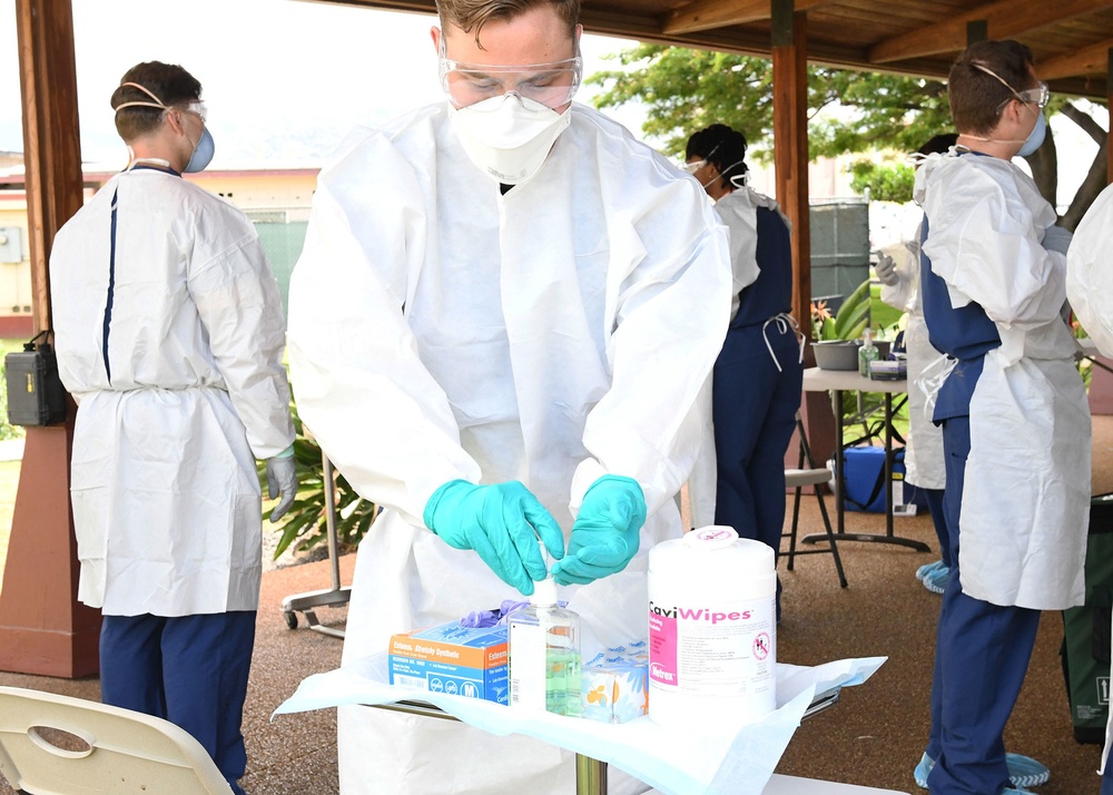 Sailor sanitizes gloves in COVID-19 testing site between patients