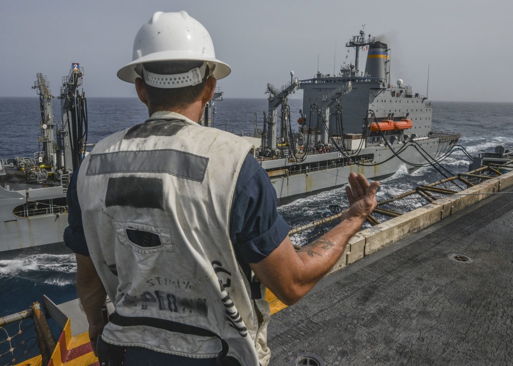 Boatswain's Mate Signals Distance Line Crew During Replenishment At Sea With Henry J. Kaiser-Class Underway Replenishment Oiler, USNS Yukon, On The Flight Deck Aboard Aircraft Carrier USS Nimitz CVN 68