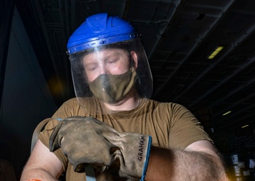 Logistics Specialist Binds Hydraulic Drums In Hangar Bay Aboard Aircraft Carrier CVN 68