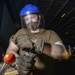 Logistics Specialist Binds Hydraulic Drums In Hangar Bay Aboard Aircraft Carrier CVN 68