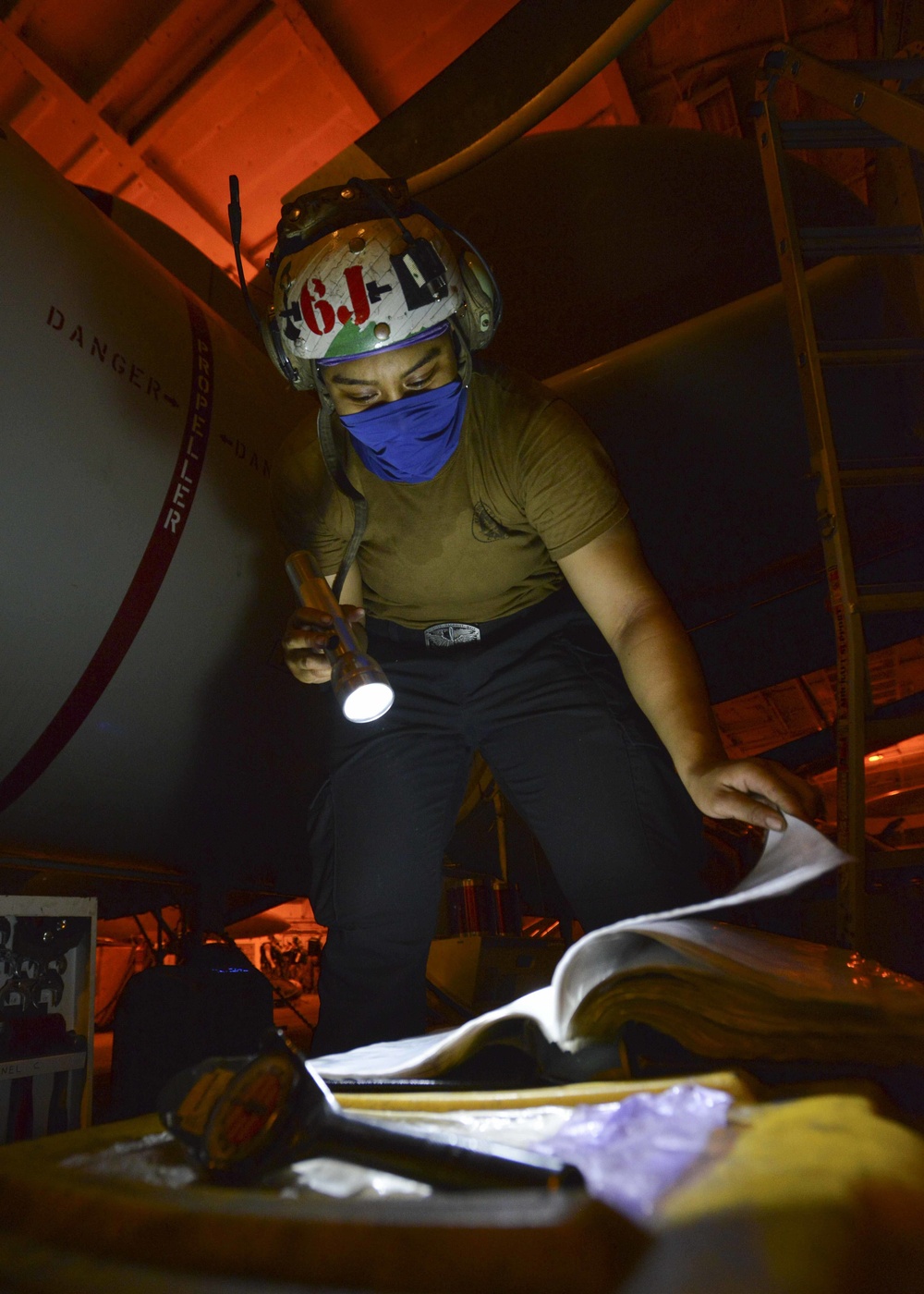 Aviation Machinist's Mate Reviews Installation Publication For Carrier Airborne Early Warning Squadron VAW 116 Sun Kings E-2C Hawkeye In Hangar Bay Aboard Aircraft Carrier USS Nimitz CVN 68