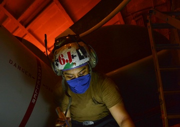 Aviation Machinist's Mate Reviews Installation Publication For Carrier Airborne Early Warning Squadron VAW 116 Sun Kings E-2C Hawkeye In Hangar Bay Aboard Aircraft Carrier USS Nimitz CVN 68