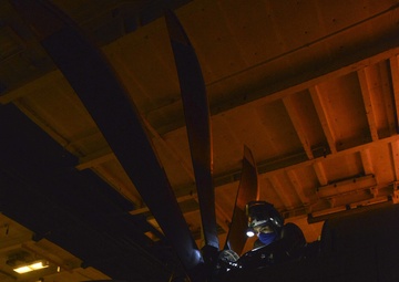 Aviation Machinist's Mate Installs Brush Block Assembly On Carrier Airborne Early Warning Squadron VAW 116 Sun Kings E-2C Hawkeye In Hangar Bay Aboard Aircraft Carrier USS Nimitz CVN 68
