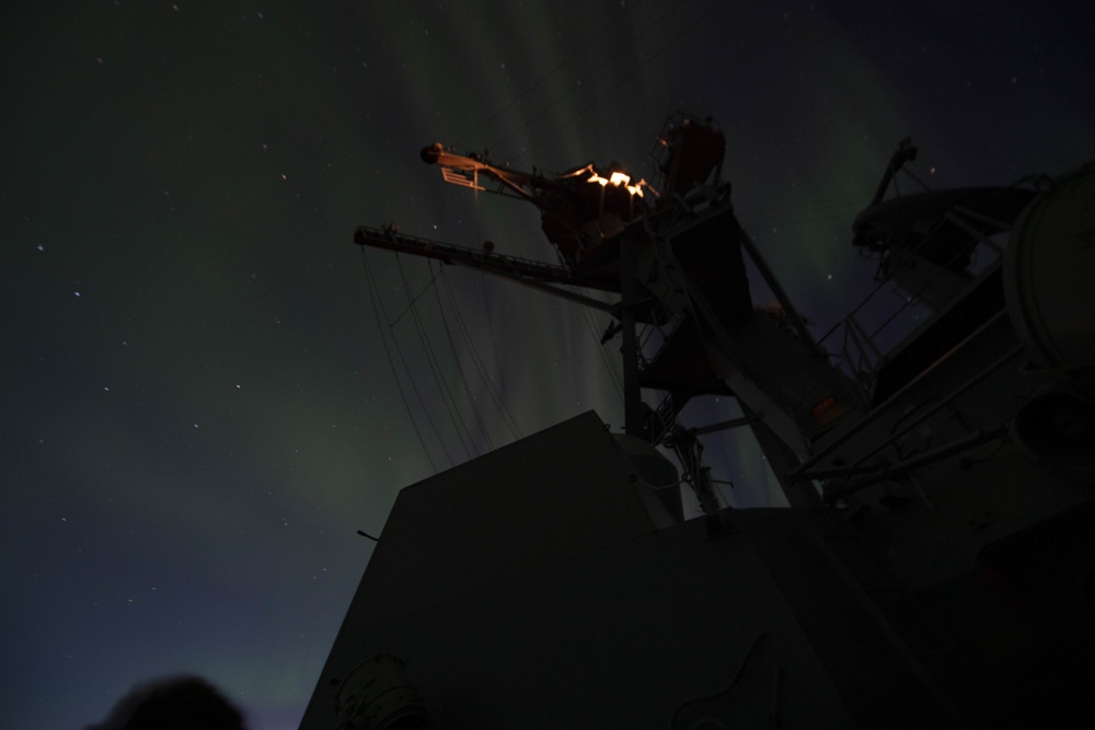 The Aurora Borealis Appears over the Arleigh Burke-class Guided-Missile Destroyer USS Thomas Hudner (DDG 116), During Operation Nanook-Tuugaalik