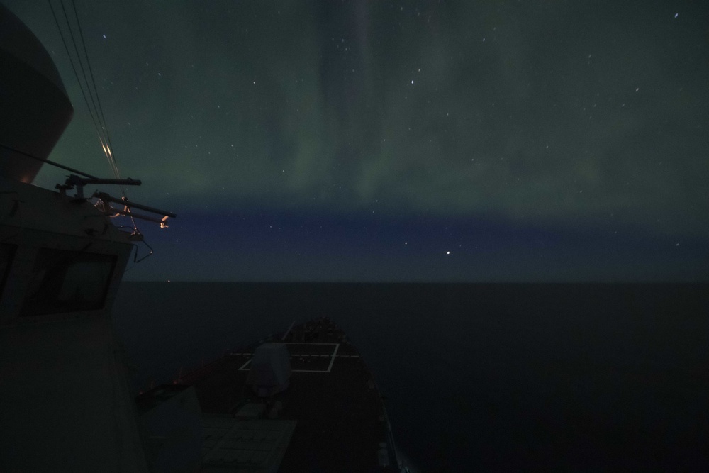 The Aurora Borealis Appears over the Arleigh Burke-class Guided-Missile Destroyer USS Thomas Hudner (DDG 116), During Operation Nanook-Tuugaalik