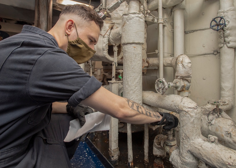 Sailor Inspects A Water Heater For Steam Leaks