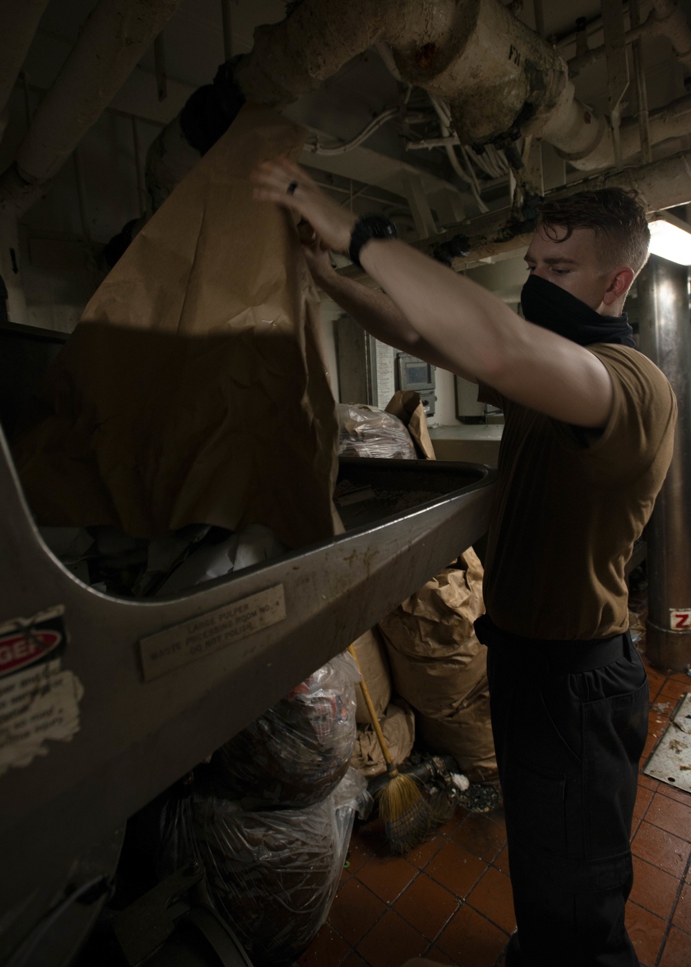 Aviation Ordnanceman Empties Paper Into Pulper Aboard Aircraft Carrier