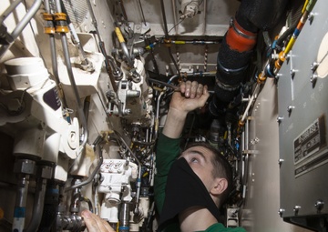 Aviation Structural Mechanic Troubleshoots Hydraulic Line In Hangar Bay Aboard Aircraft Carrier USS Nimitz CVN 68