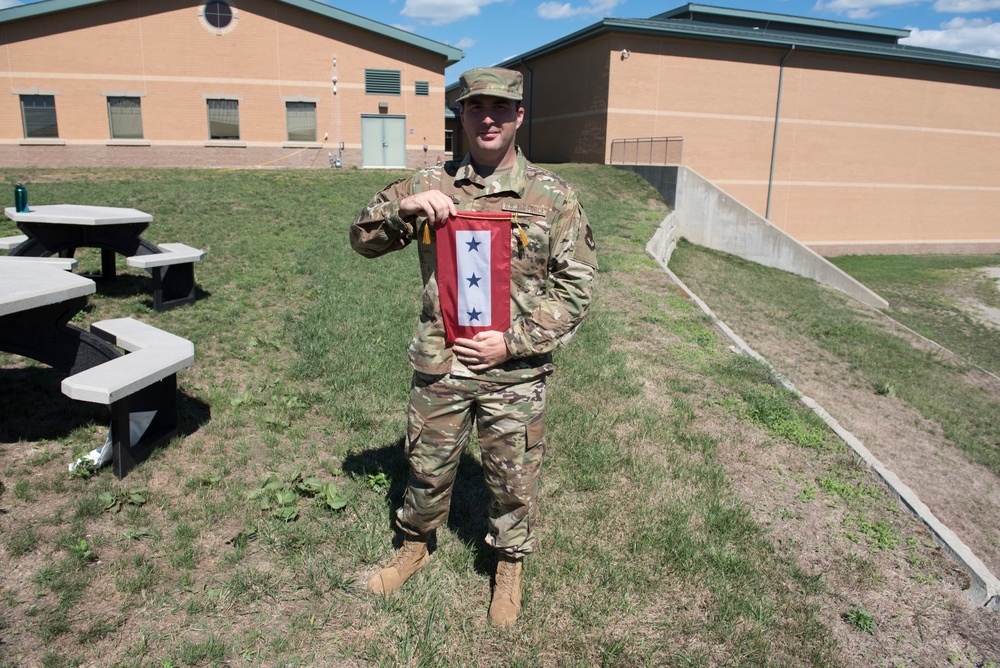 Senior Airman David Williams poses for a photo with the Three Blue-Star Service Banner