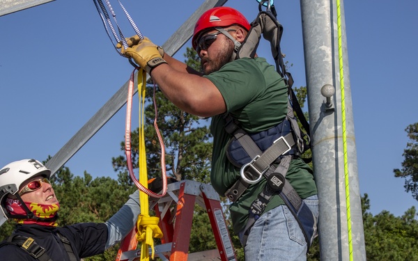 Electronic maintenance teams practice tower climbing to keep base communications flowing