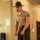 A U.S. Marine Corps Drill Instructor is photographed in what appears to be a barracks hallway, shouting with clenched fists in a commanding posture. He is wearing the distinctive campaign cover (drill instructor hat), khaki service uniform with visible rank insignia and service ribbons. The setting and uniform are consistent with a military training environment.