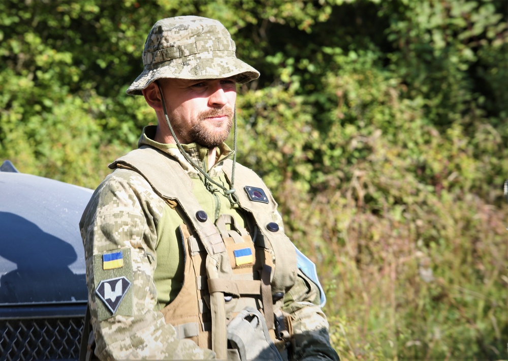 A Ukrainian soldier stands in front of a vehicle during Combined Resolve