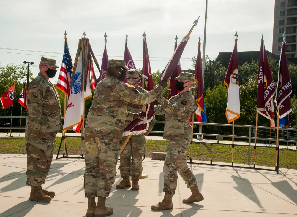 Brig. Gen. Lisa L. Doumont passes the guidon to Brig. Gen. Joseph A. Marsiglia during a change of command ceremony for the Medical Readiness and Training Command