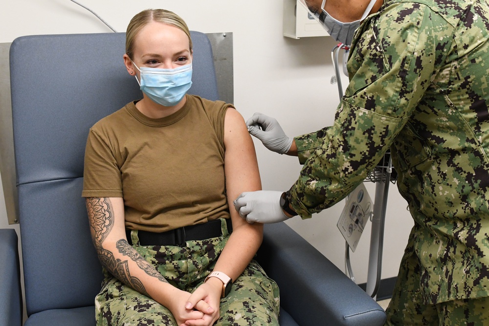 Hospital Corpsman disenfects Sailor's arm prior to vaccine