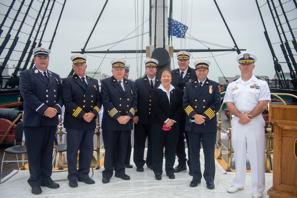 Cmdr. John Benda, Commanding Officer of USS Constitution, poses with Boston Fire Department during a commemoration aboard the ship honoring the nearly 3,000 lives lost and all those affected by the Sept 11