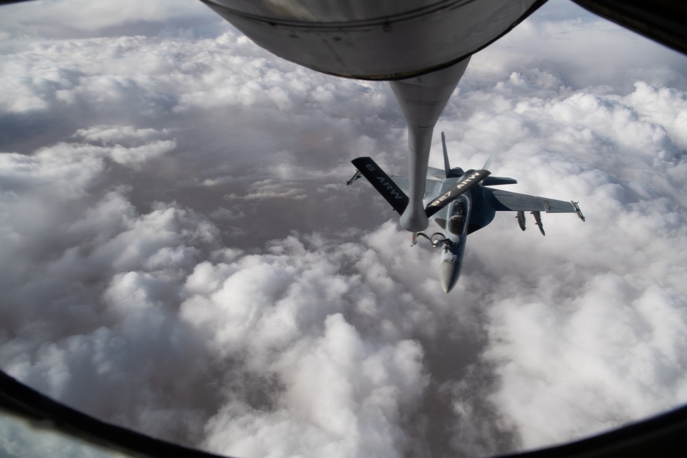 A U.S. Air Force KC-135 Stratotanker refuels Navy F/A-18 Super Hornets