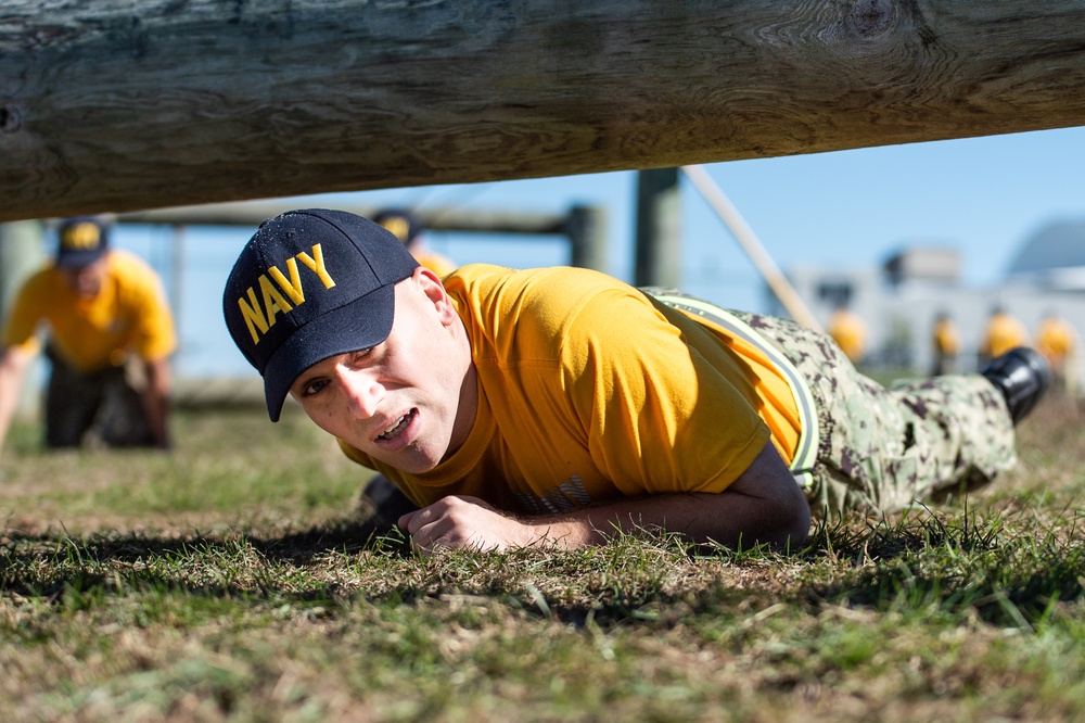 201014-N-TE695-0058 NEWPORT, R.I. (Oct. 14, 2020)  Navy Officer Candidate School (OCS) student low crawls at the obstacle course during battle stations