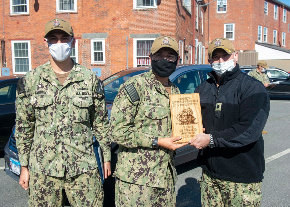 Aviation electrician's mate 3rd Class Zachary HansenMcPhail, middle, assigned to USS Constitution, is awarded Junior Sailor of the Quarter