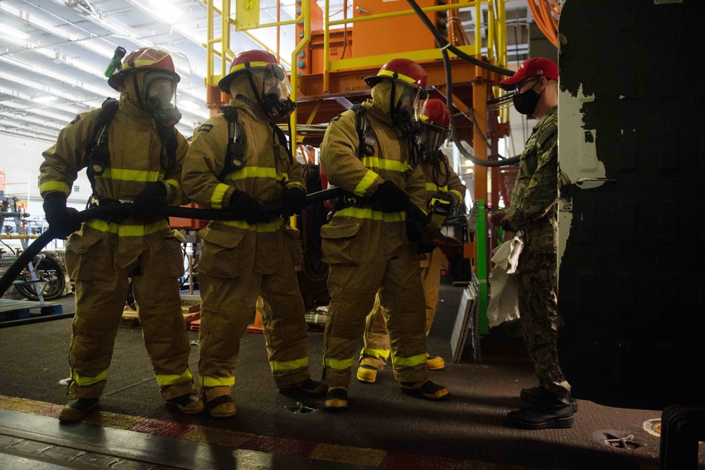 U.S. Navy Sailors prepare to fight a simulated fire during an in-port emergency drill in the hangar bay aboard the aircraft carrier USS John C. Stennis (CVN 74) in Norfolk, Virginia, Oct. 24, 2020.