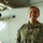 A U.S. Army soldier in Operational Camouflage Pattern (OCP) uniform is standing in front of a white aircraft inside a hangar. The soldier is smiling and appears to be posing for an official or documentary-style photograph. A name tape reading 'NIGRO' and a 'U.S. ARMY' tape are clearly visible on the uniform.