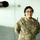 A U.S. Army soldier named Ramosayala is posing in front of what appears to be a military or government aircraft inside a hangar. The soldier is wearing the Army Combat Uniform (ACU) in OCP (Operational Camouflage Pattern) and is smiling at the camera. The name tape reads 'RAMOSAYALA' and the branch tape reads 'U.S. ARMY'.