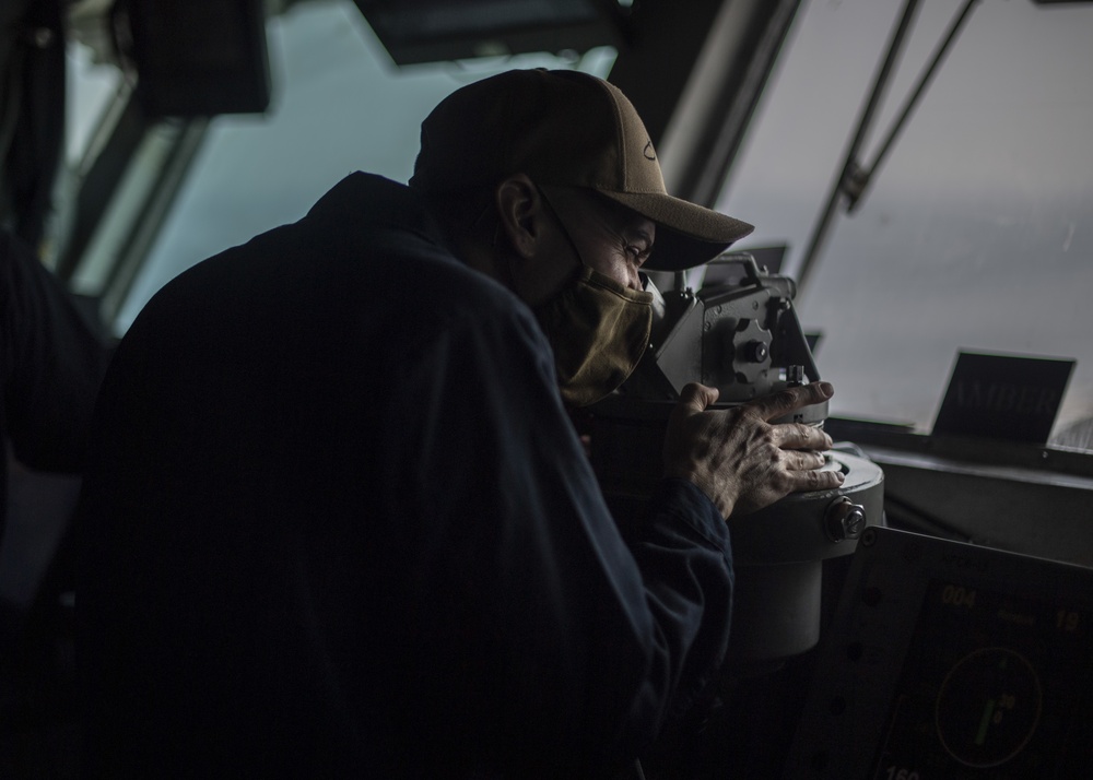 Sailor looks through a Sextant aboard USS Nimitz