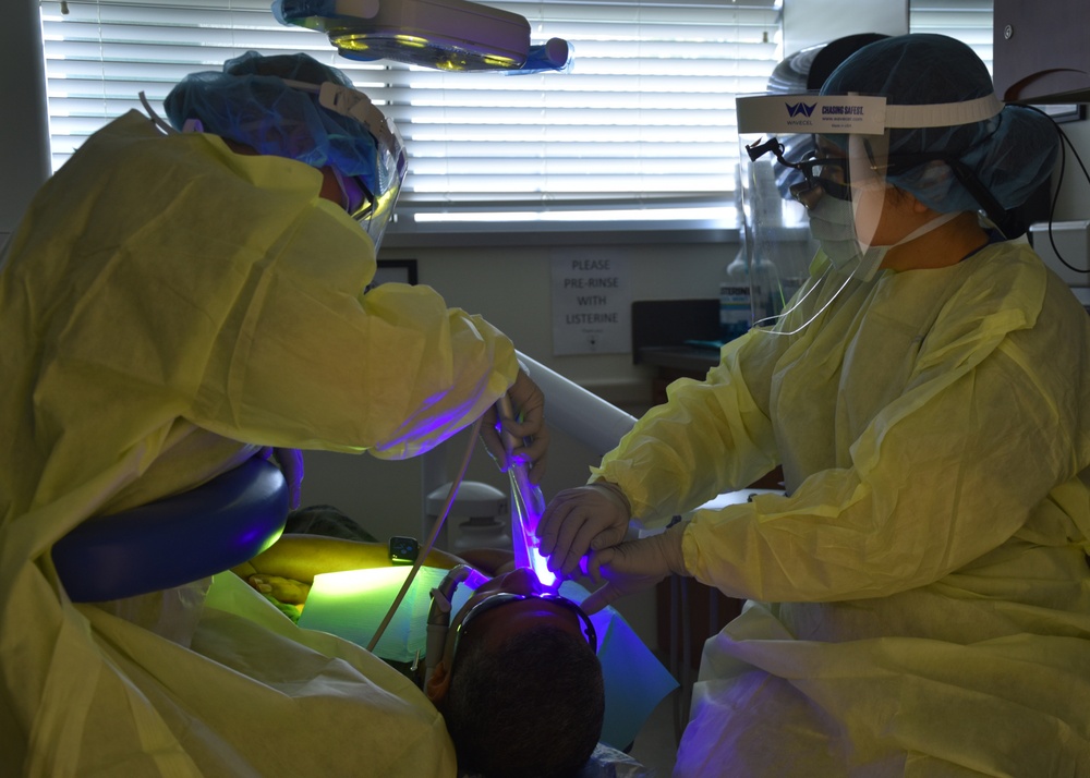 Hospitalman Hailey Lavoie (left) and Lt. Cmdr. Calen Lee perform a dental procedure on a patient