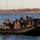 Sweden and U.S. Strengthen Maritime Capabilities During Swedish-led Bilateral Exercise The image shows a group of military or special operations personnel aboard one or two black inflatable rubber raiding craft (IRBCs/RHIBs) near a shoreline. Personnel are wearing tactical gear, dark uniforms, and communications headsets, with some individuals having their faces obscured. The setting appears to be a cold-weather coastal or lake environment with sparse autumn/winter vegetation visible in the background.
