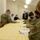 Guard medical team supports Czech partners A group of military personnel and civilians are gathered around a table with a yellow patterned tablecloth, appearing to be in a briefing or documentation session. Several individuals in U.S. Army camouflage uniforms are writing on documents or clipboards, while civilian counterparts stand across the table. All participants are wearing face masks, suggesting this took place during the COVID-19 pandemic period.