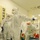 Guard medical team supports Czech partners Multiple personnel wearing full personal protective equipment (PPE) are gathered in what appears to be a medical or clinical facility. They are dressed in white Tyvek-style hazmat suits with blue gloves, blue shoe covers, face shields, and respirator masks. One individual is holding a spray bottle and appears to be conducting decontamination procedures while another gestures directionally.