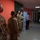 Guard medical team visits Czech Military University Hospital Prague A group of U.S. Army soldiers in OCP (Operational Camouflage Pattern) uniforms are gathered in a corridor with orange walls, facing two civilians. All individuals are wearing face masks, suggesting this interaction took place during the COVID-19 pandemic period. The setting appears to be an institutional building, possibly a hospital or administrative facility.