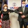 Two masked individuals are performing an elbow bump greeting in front of a USAID (United States Agency for International Development) banner. They are flanked by the American flag on the left and what appears to be the flag of El Salvador or a similar Central American nation on the right. The setting appears to be an official meeting or diplomatic event, likely during the COVID-19 pandemic period.