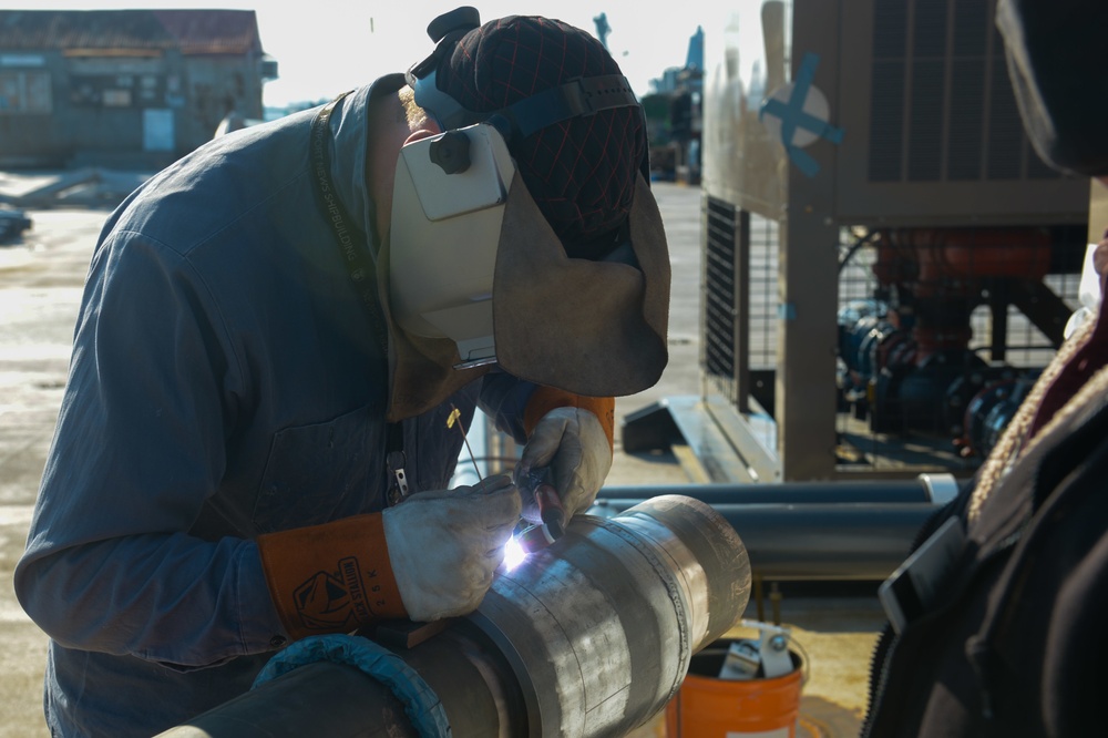 Shipyard worker welds pipe