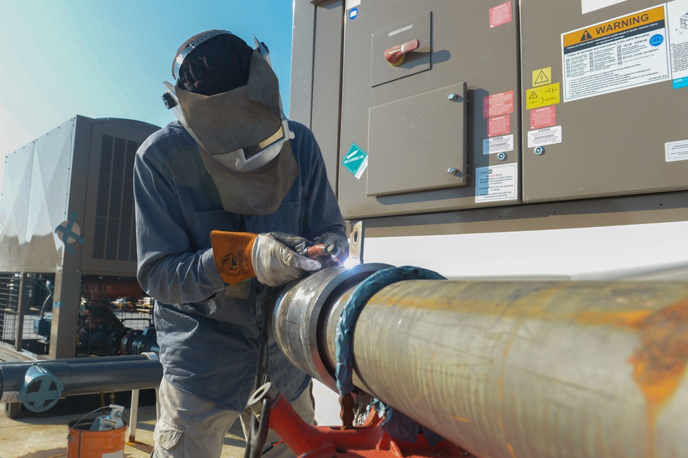 Shipyard worker welds pipe