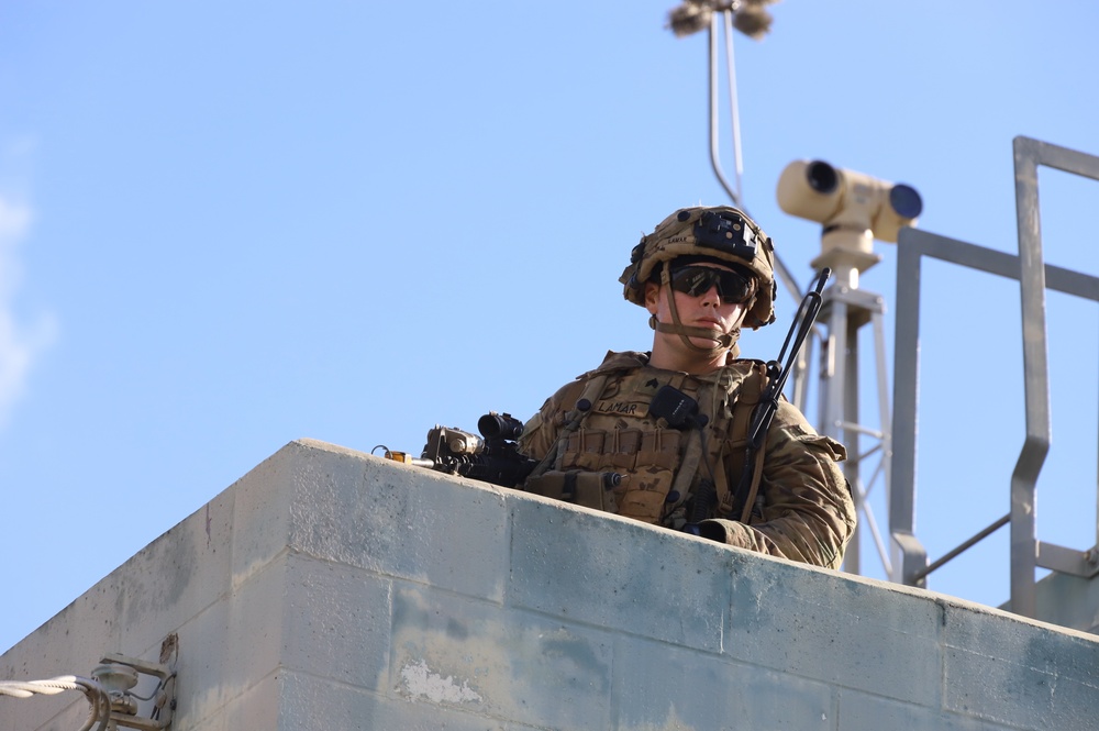 25ID Soldier watches for enemy movements from roof of building at JRTC