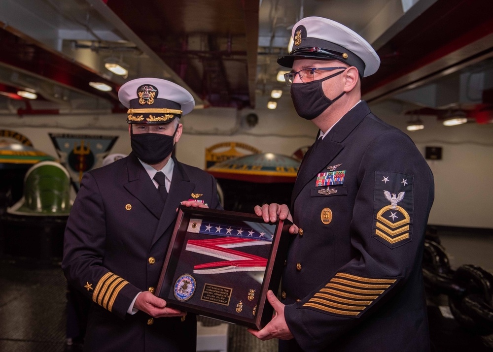 Command Master Chief Marc Puco (right), presents Capt. Randy Peck, commanding officer of the aircraft carrier USS John C. Stennis (CVN 74), with his commissioning pennant, during a change of command ceremony