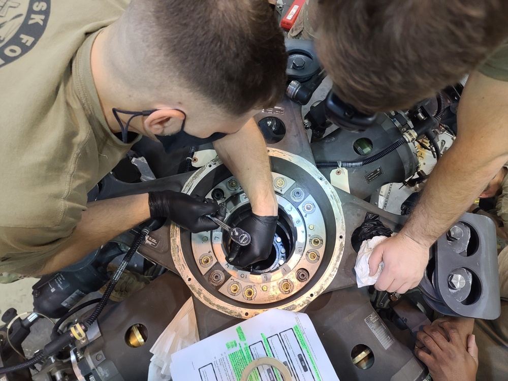 Soldiers working on the main rotor head on a UH-60 Black Hawk helicopter.