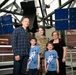 Chief Master Sergeant April Brittain poses with family in front of satellite static model after transfer ceremony into USSF