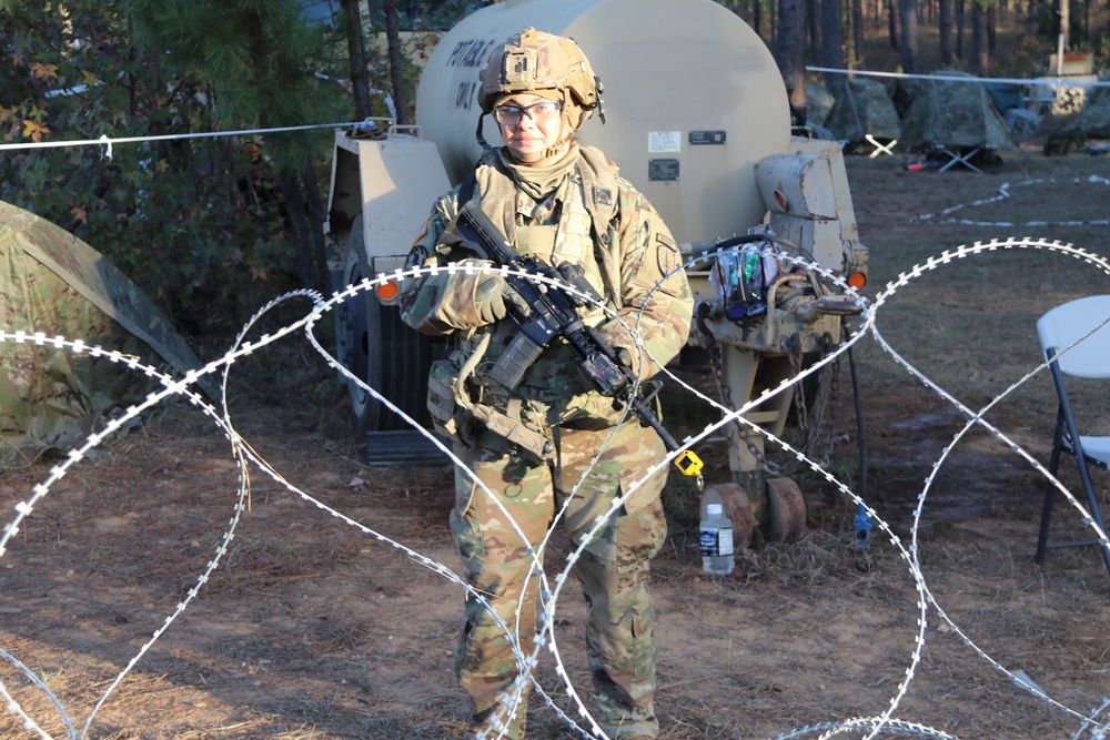 5th SFAB Soldier with weapon behind C-Wire guarding waterbuffalo at JRTC.