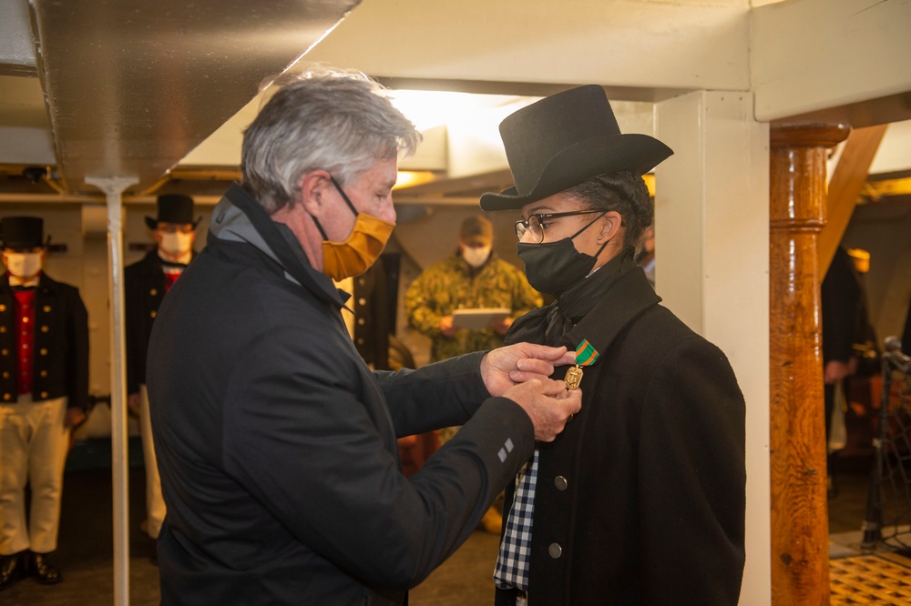 Secretary of the Navy Kenneth J. Braithwaite awards Seaman Jaida Williams with a Navy and Marine Corps Achievement medal aboard USS Constitution