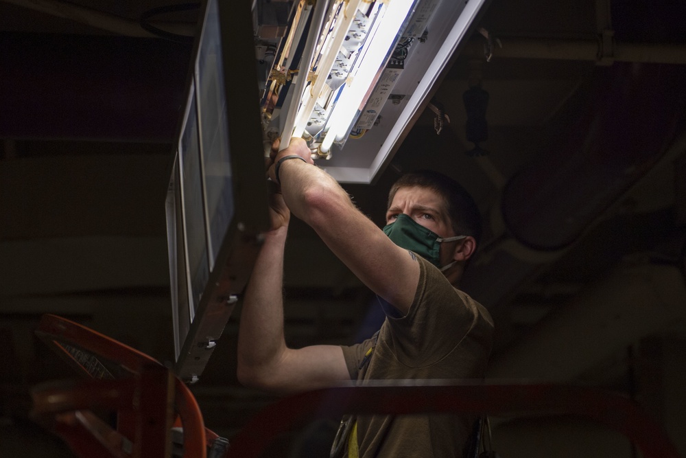 USS America (LHA 6) Sailor Inspects Lighting Equipment